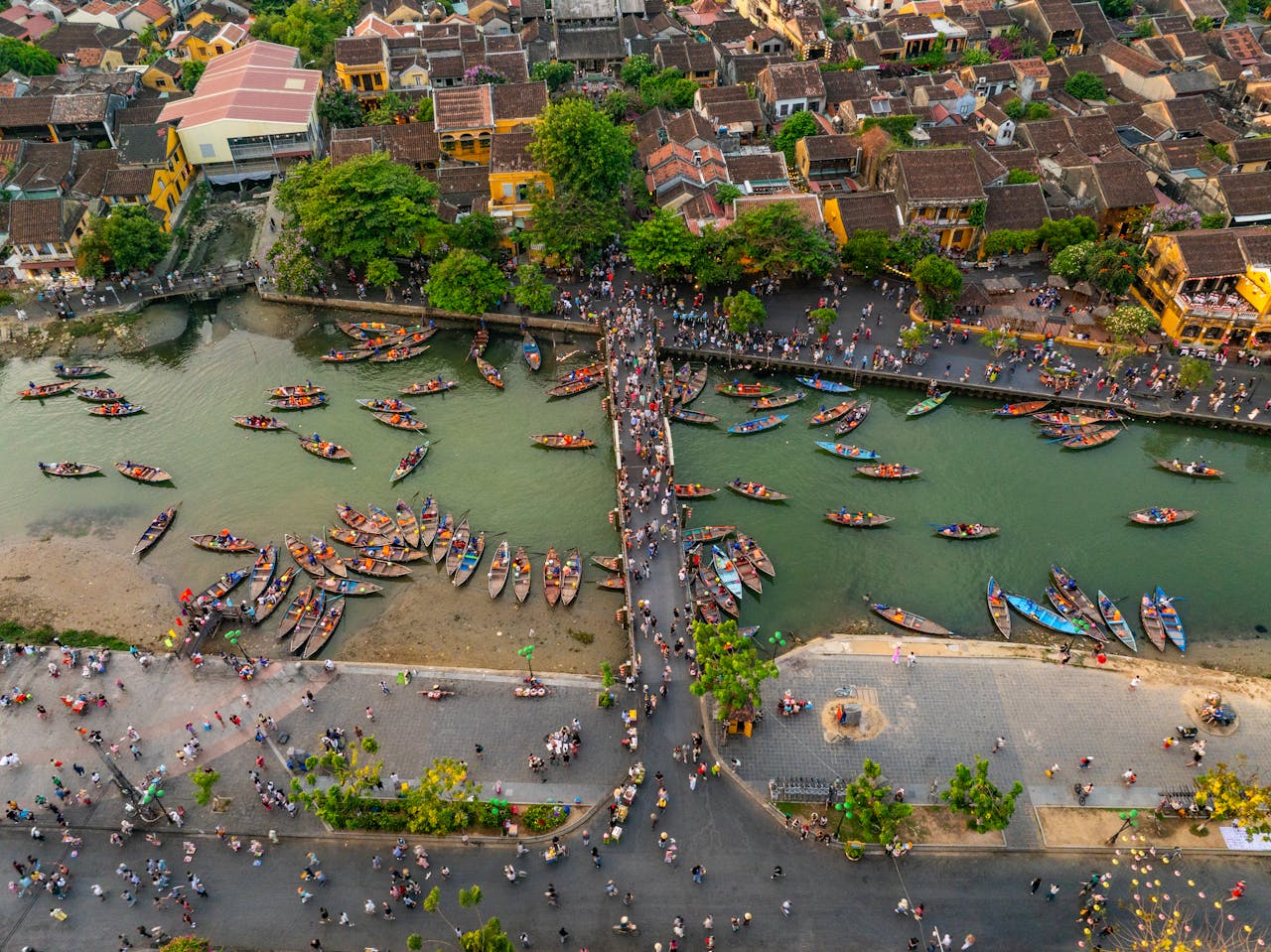 A vibrant aerial scene of Hội An's waterfront with boats and a bustling night market.